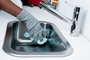 A person cleaning the sink to illustrate cleaning services in NYC.