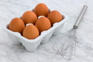 an image of six brown eggs and a whisk, read about what to eat and wear on a moving day
