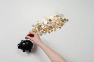 A person putting coins into a piggy bank.
