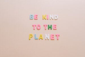 Words " be kind to the planet" on pink wallpaper