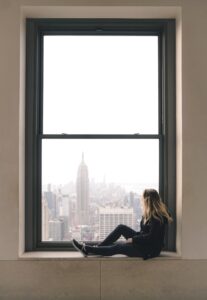 A girl sitting by the window and enjoying the view.