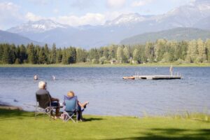 2 people sitting near a lake 