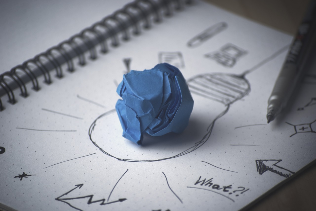 A blue paper ball on a piece of paper with a light bulb drawn on it.