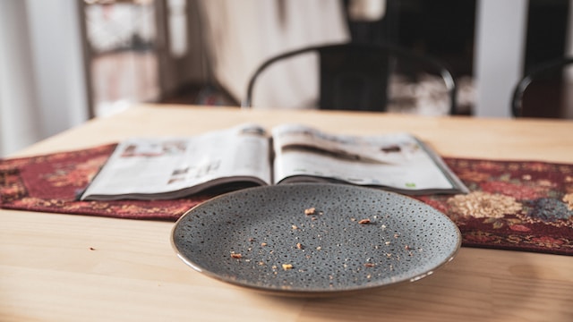 A dirty plate an an open magazine on a table.